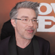 André Nemec, a white man with styled grey hair wearing all black and glasses, speaking on the red carpet at the premiere of Cowboy Bebop.
